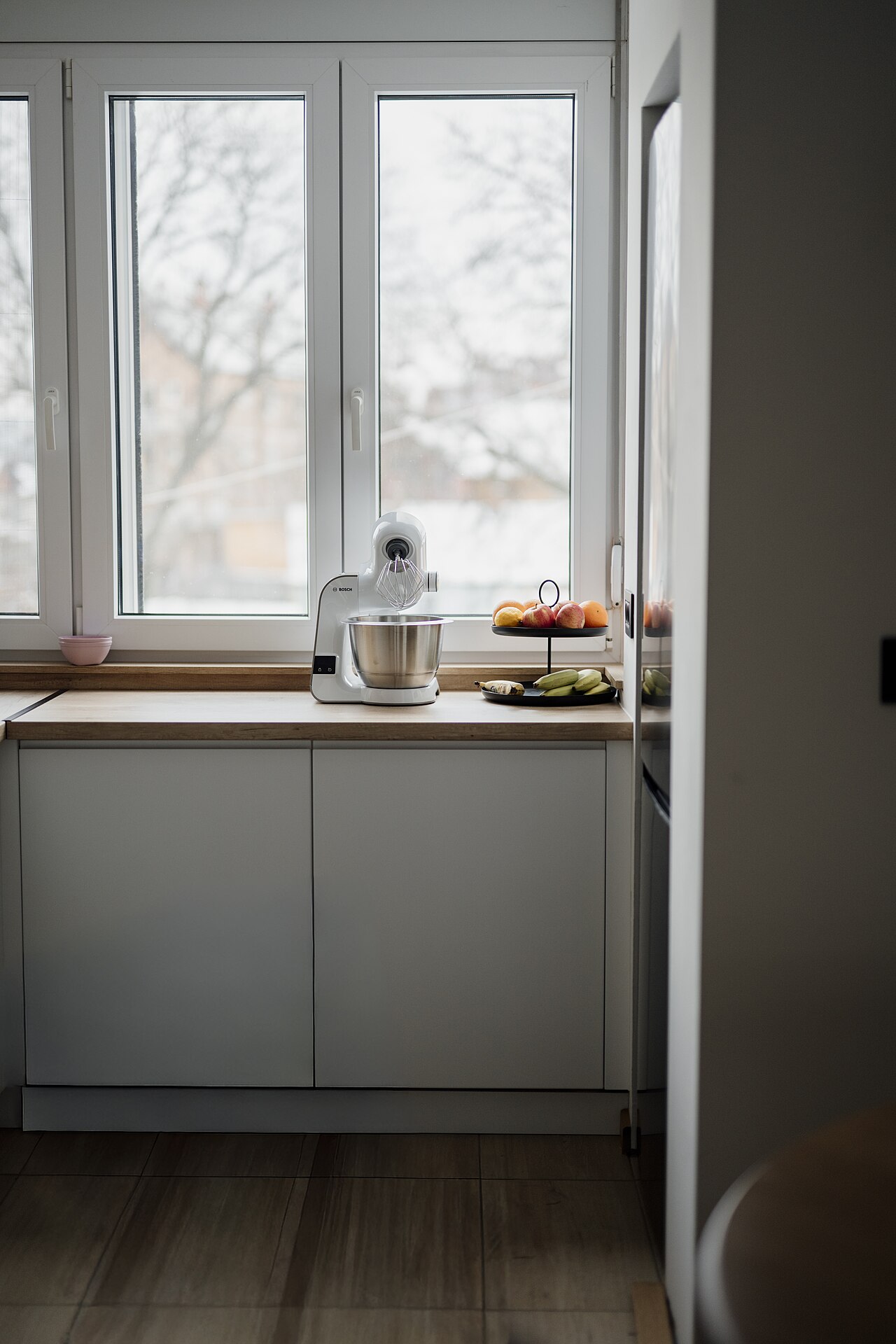 Kitchen countertop by a window with a stand mixer and fruit bowl
